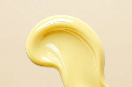 Gelbliche Creme-Textur auf beigem Hintergrund (Retinol)